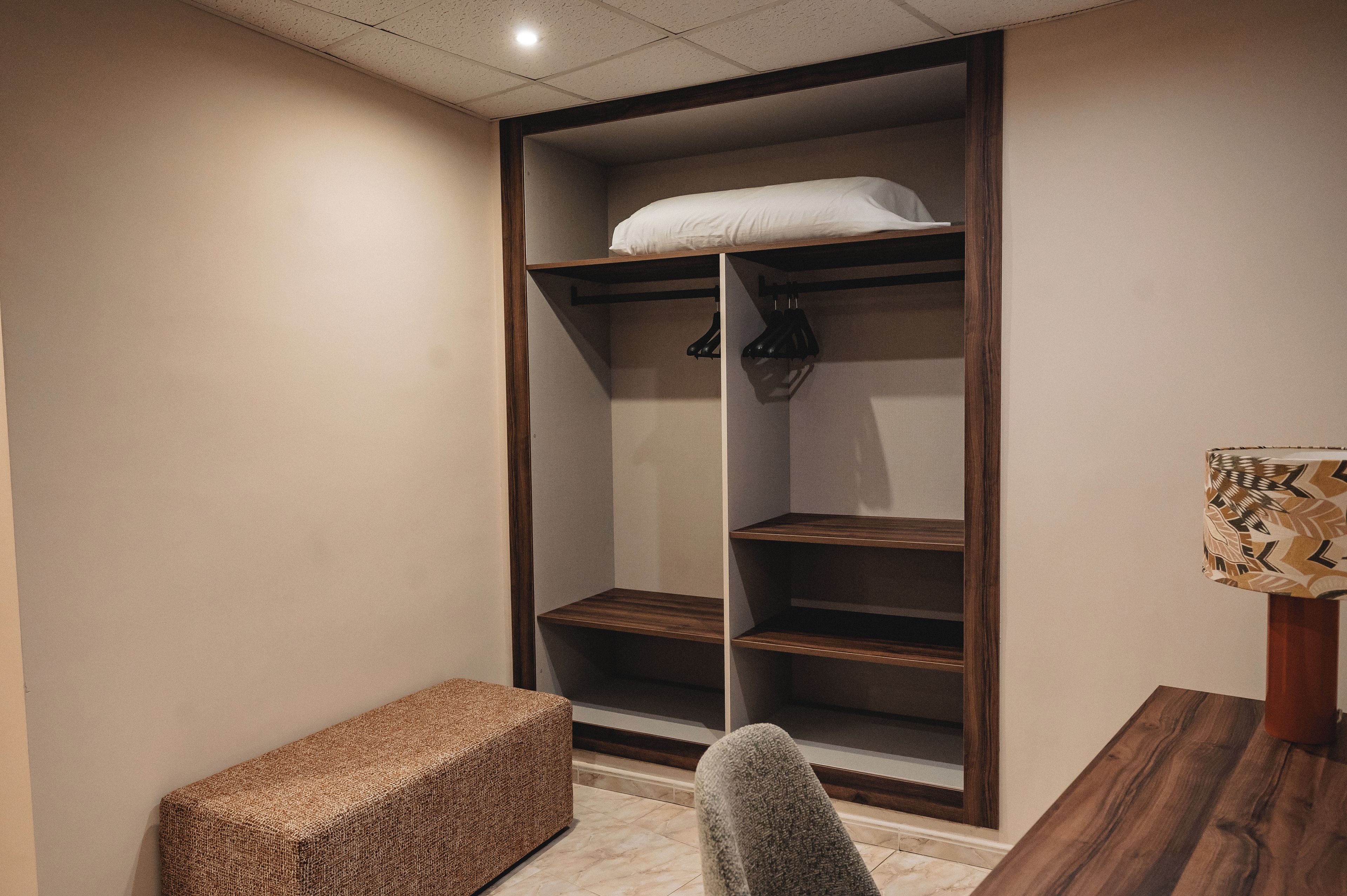 A room with a built-in closet featuring shelves and hanging space.
