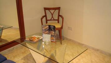 A glass-top table with a chair and a brochure stand in a room with a tiled floor.