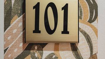 Ein Schild mit der Zimmernummer 101 an einer strukturierten Wand.