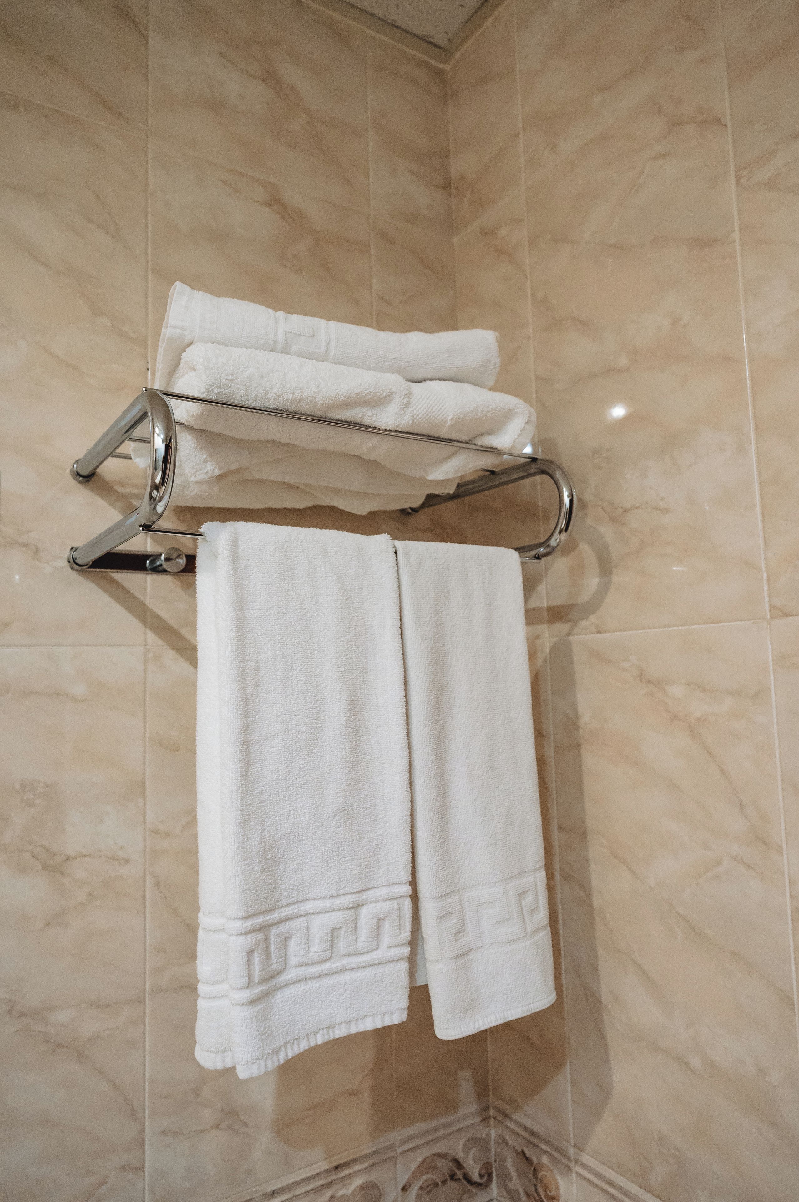 Ein Badezimmer mit Handtuchhalter, zwei weißen Handtüchern und einer Marmorwand.