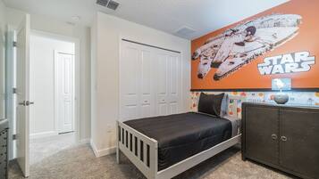 A bedroom with a Star Wars-themed wall, a bed, a wardrobe, and a door.
