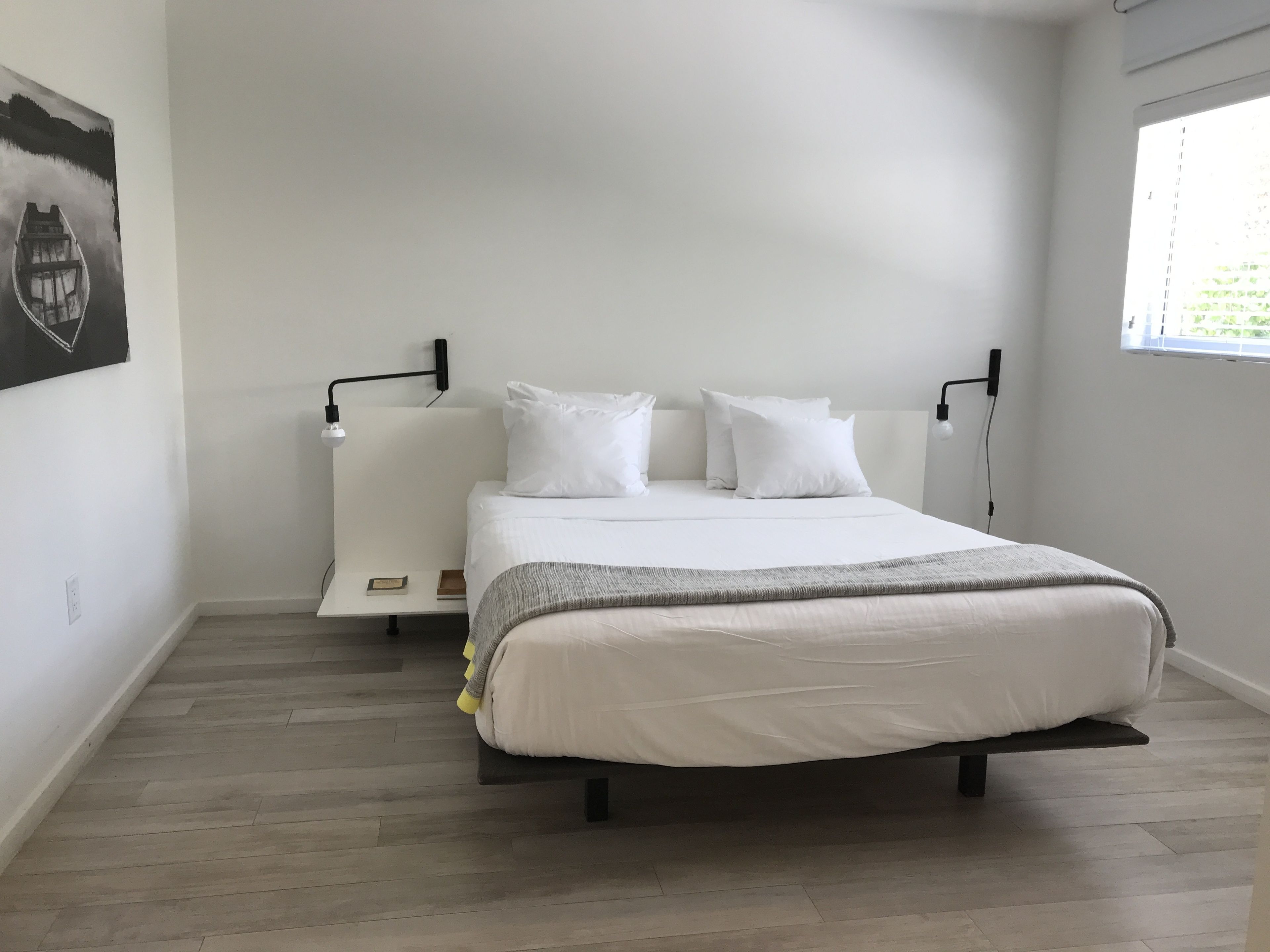 Un dormitorio minimalista con una cama, mesitas de noche y una ventana.