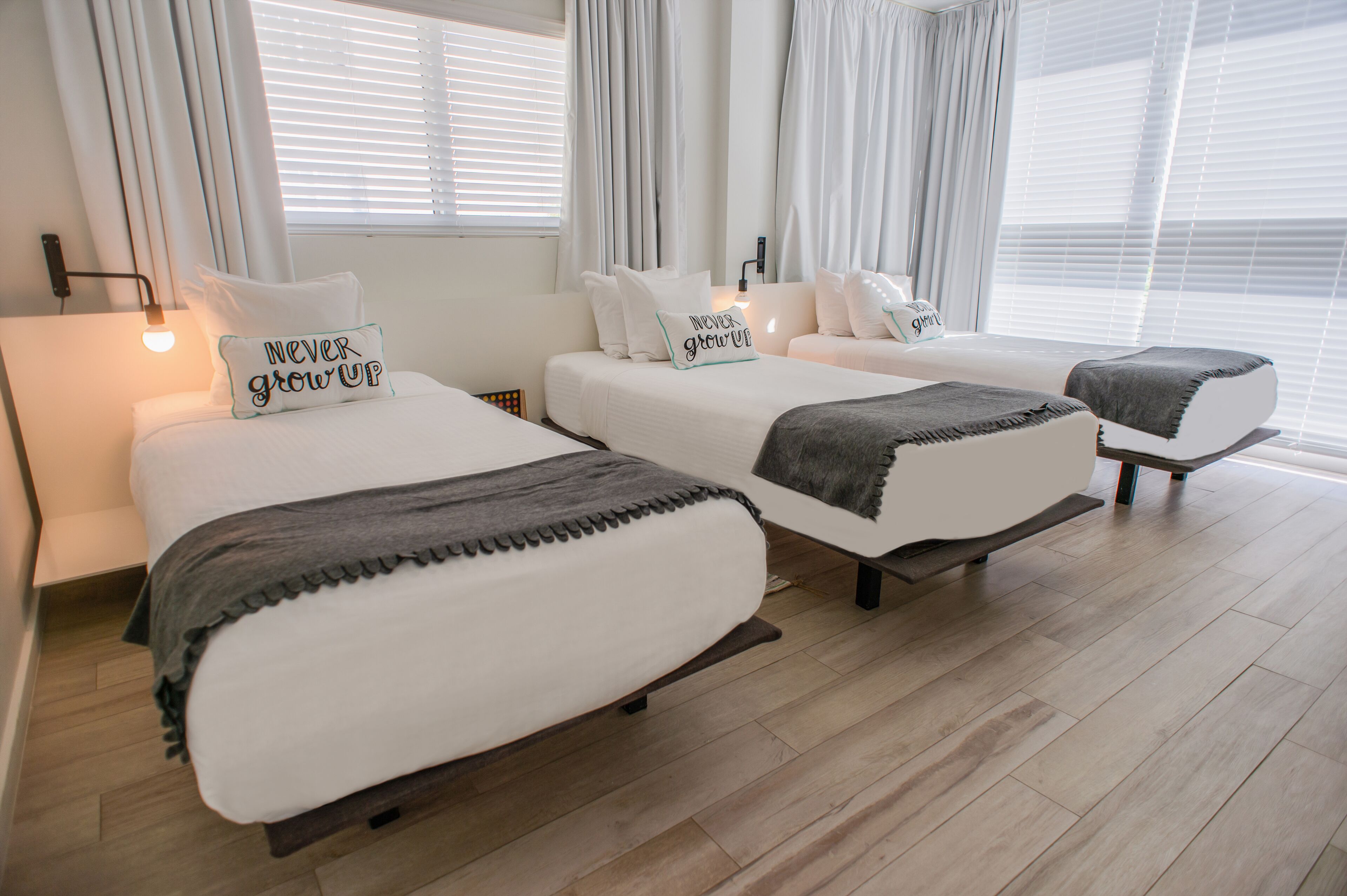 Ein Hotelzimmer mit drei Betten, weißer Bettwäsche und Holzboden.