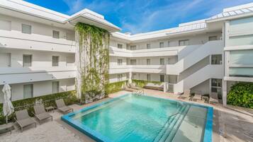 Una piscina al aire libre, sombrillas, sillones reclinables de piscina