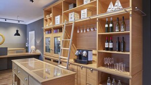 A modern bar area with wooden shelves displaying tea boxes, wine bottles, and glasses. - Hapimag Resort Hamburg (Hamburg)