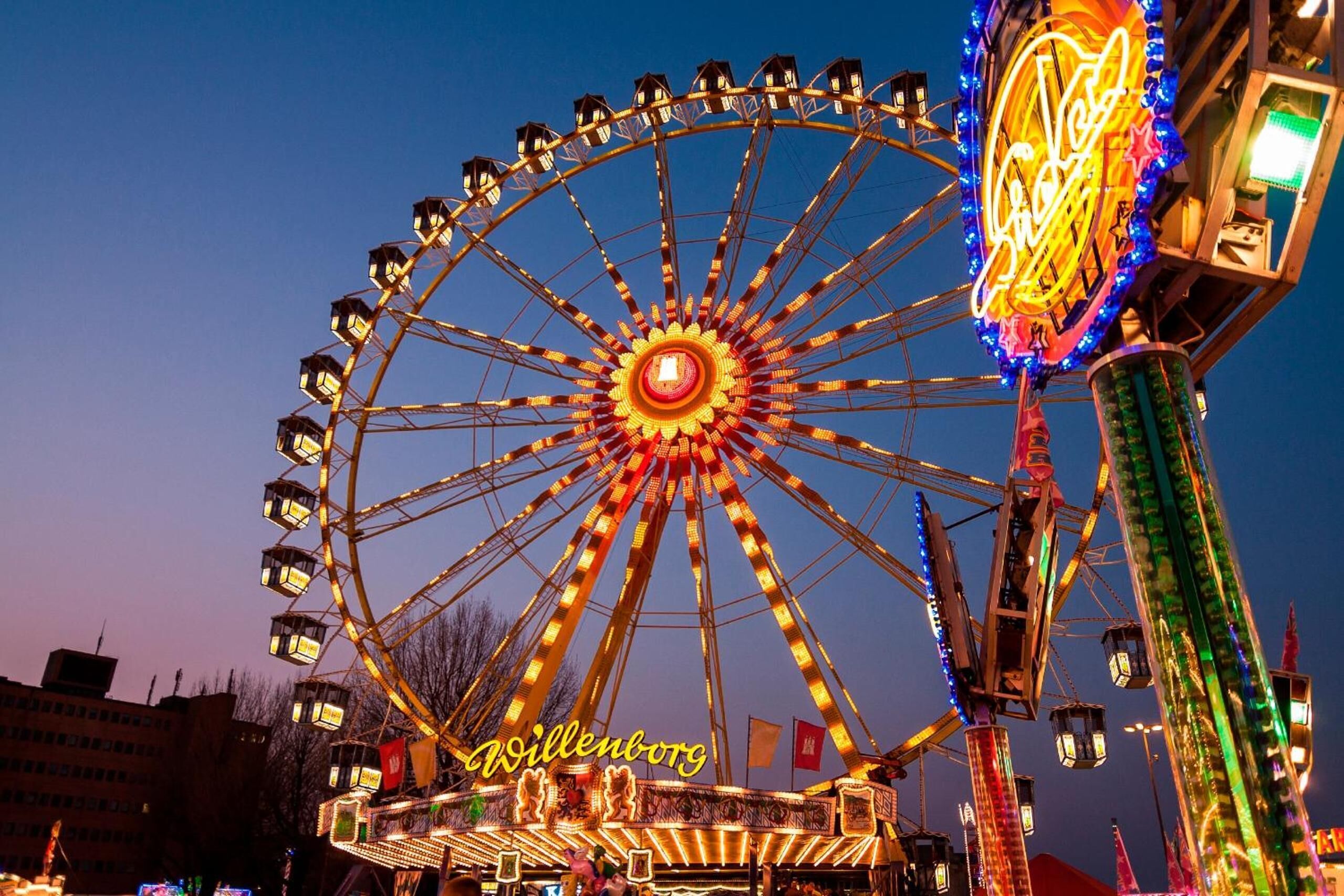 A Ferris wheel with lights and a sign that reads "Willemborgs".