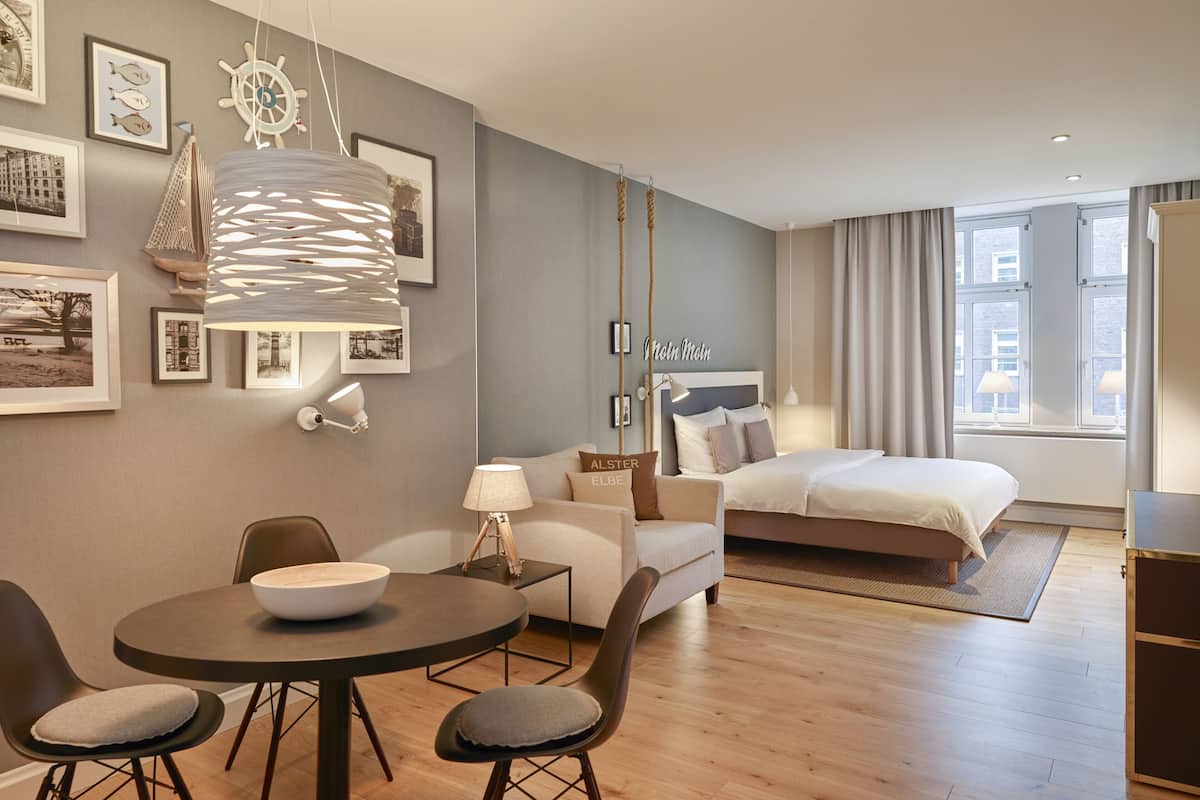 Habitació d'hotel moderna amb llit, zona de menjador i saló.