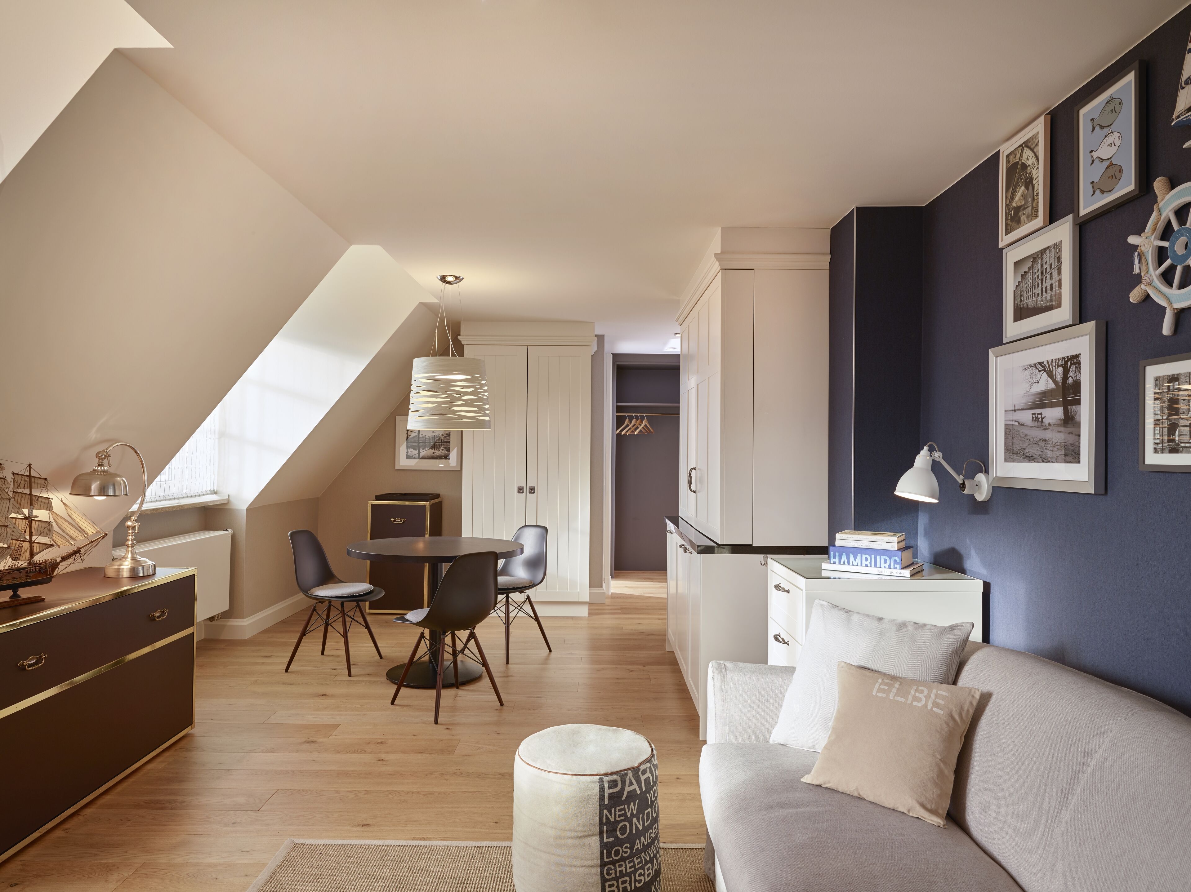 A modern loft apartment with a dining area, a sofa, and a kitchenette.