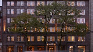 A multi-story hotel with a brick facade, multiple windows, and a tree in front. - Hapimag Resort Hamburg (Hamburg)