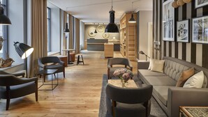 A modern living room with a sofa, chairs, a coffee table, and a bookshelf. - Hapimag Resort Hamburg (Hamburg)