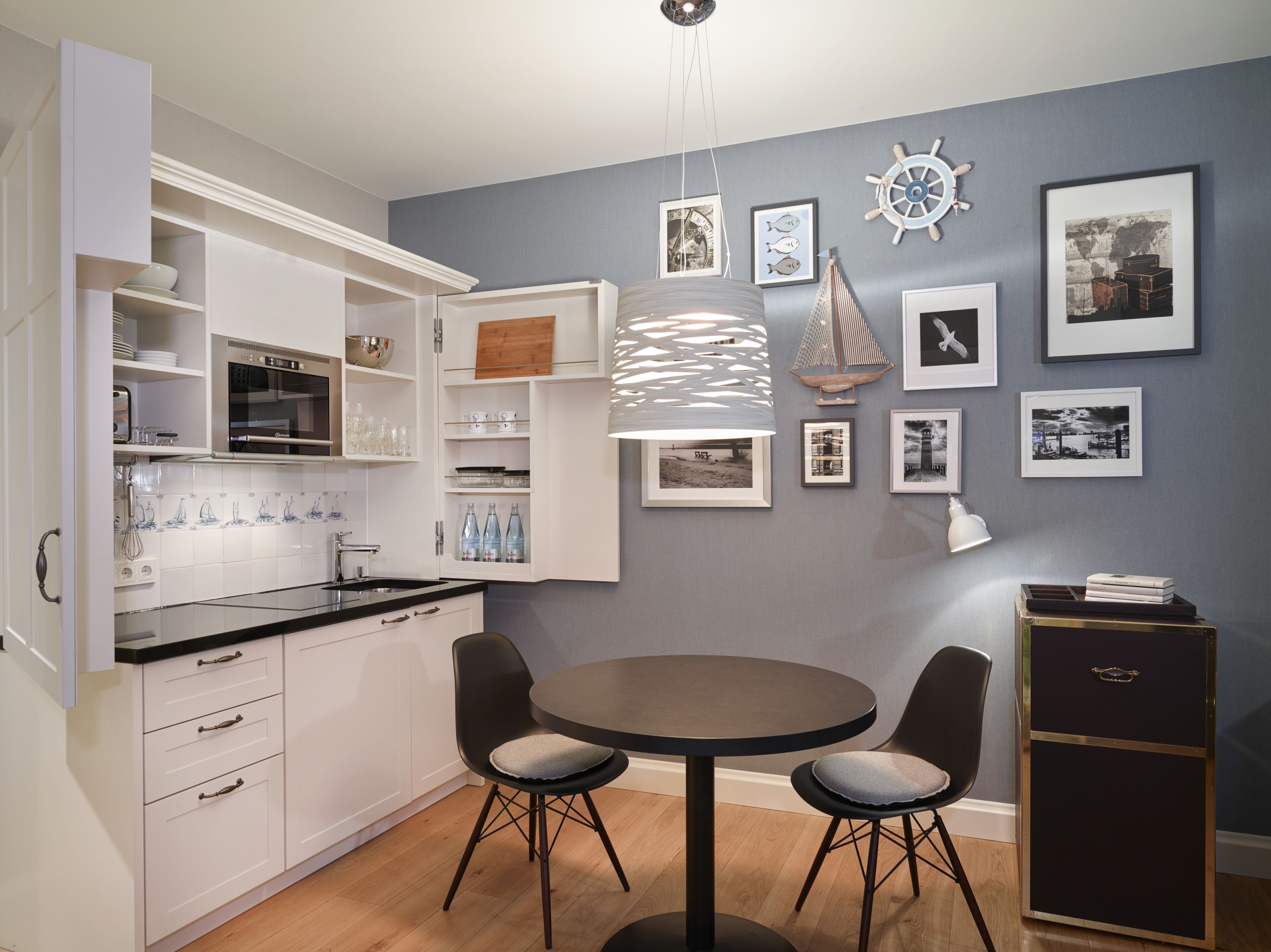 A modern kitchen with white cabinetry, a round dining table, and a black chair.