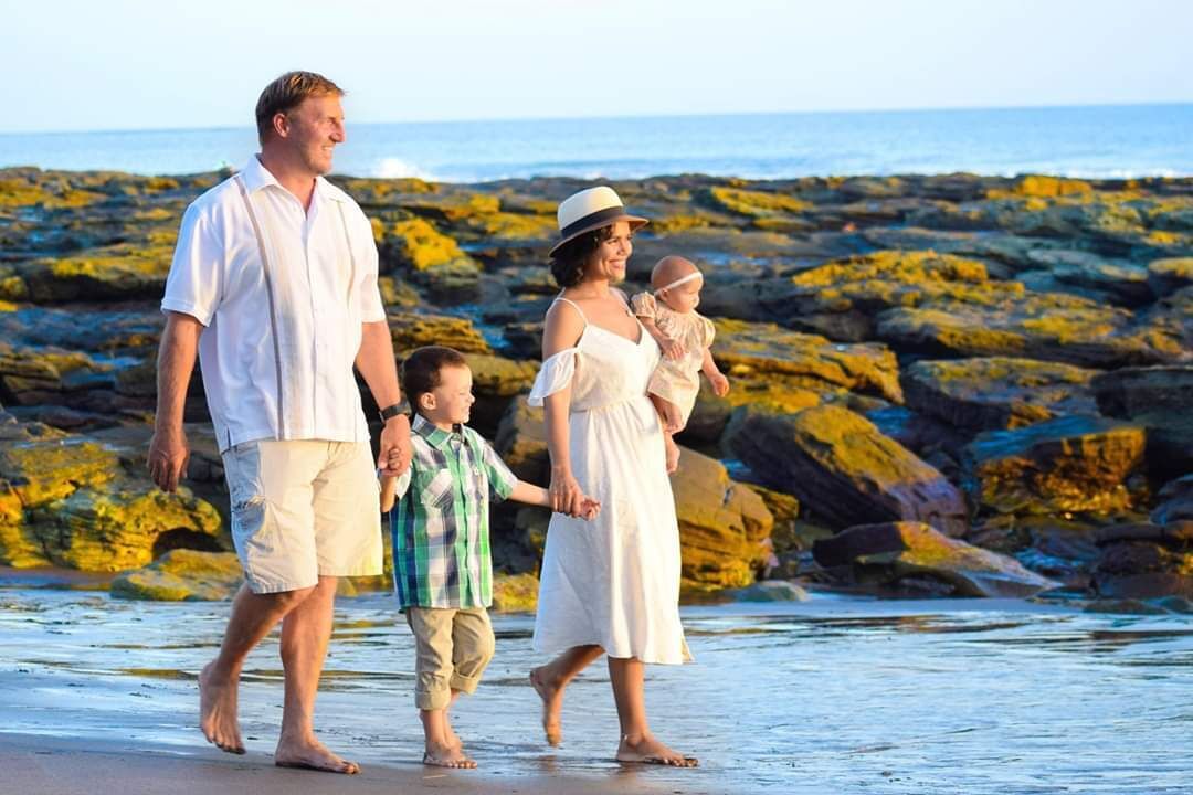 A family walking on a rocky beach with the ocean in the background.