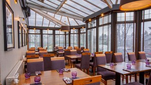 A spacious restaurant with high ceilings and large windows, featuring multiple dining tables and chairs. - The Ferryhill House Hotel (Aberdeen)