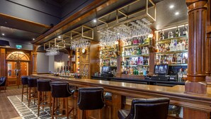 A bar area with wooden bar stools, a checkered floor, and a variety of bottles and glasses on shelves. - The Ferryhill House Hotel (Aberdeen)