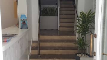 Un pasillo con suelo de mármol que conduce a una escalera.