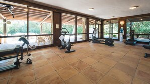 A spacious gym with various exercise equipment, large windows, and a view of the outdoors. - Roccamare Resort - Hotel Casa di Levante (Castiglione della Pescaia)