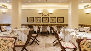 A dining area with tables and chairs, framed artwork on the wall, and a tiled floor. - Roccamare Resort - Hotel Casa di Levante (Castiglione della Pescaia)