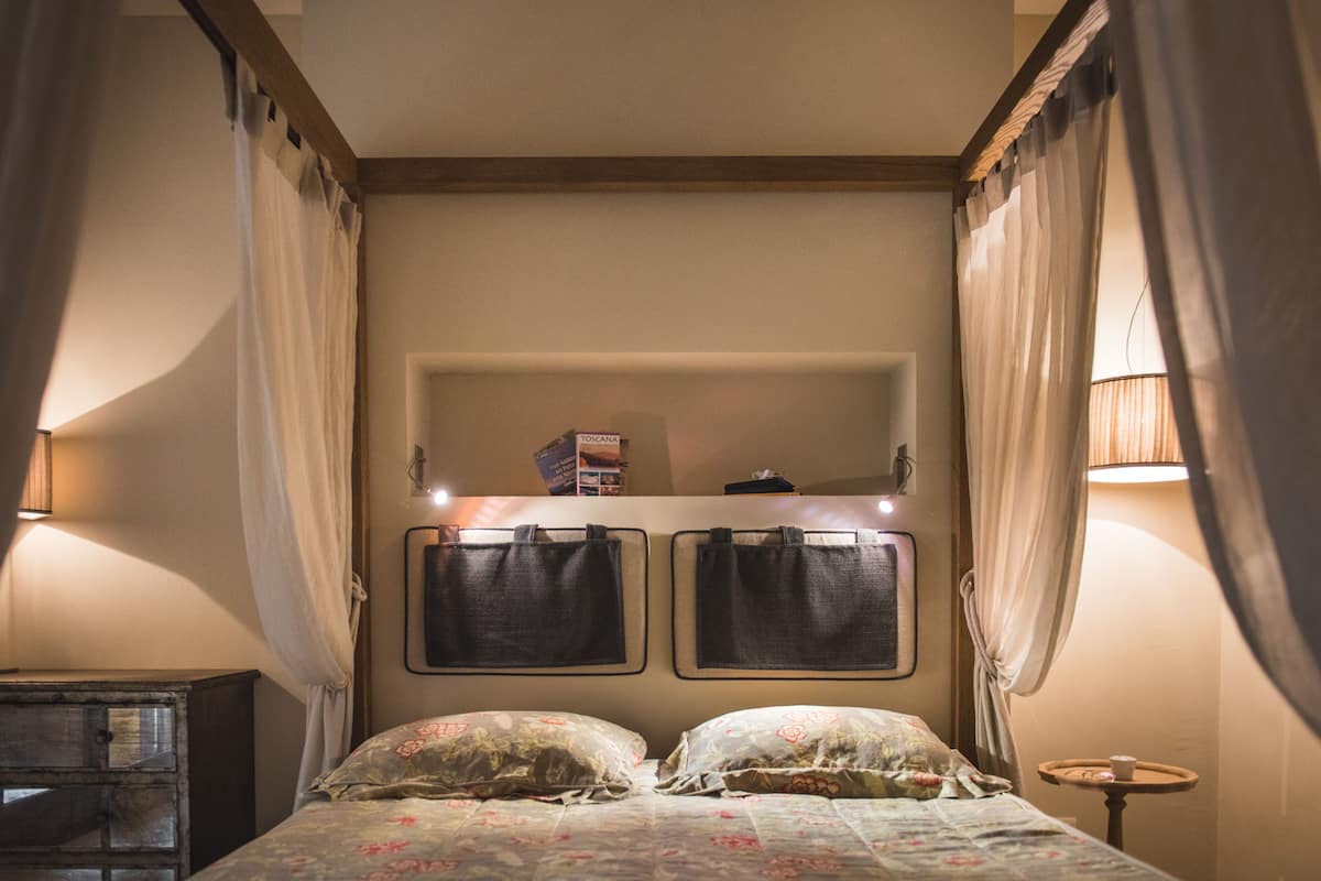 A bedroom with a bed, two bedside tables, a nightstand, and a small table with a lamp.