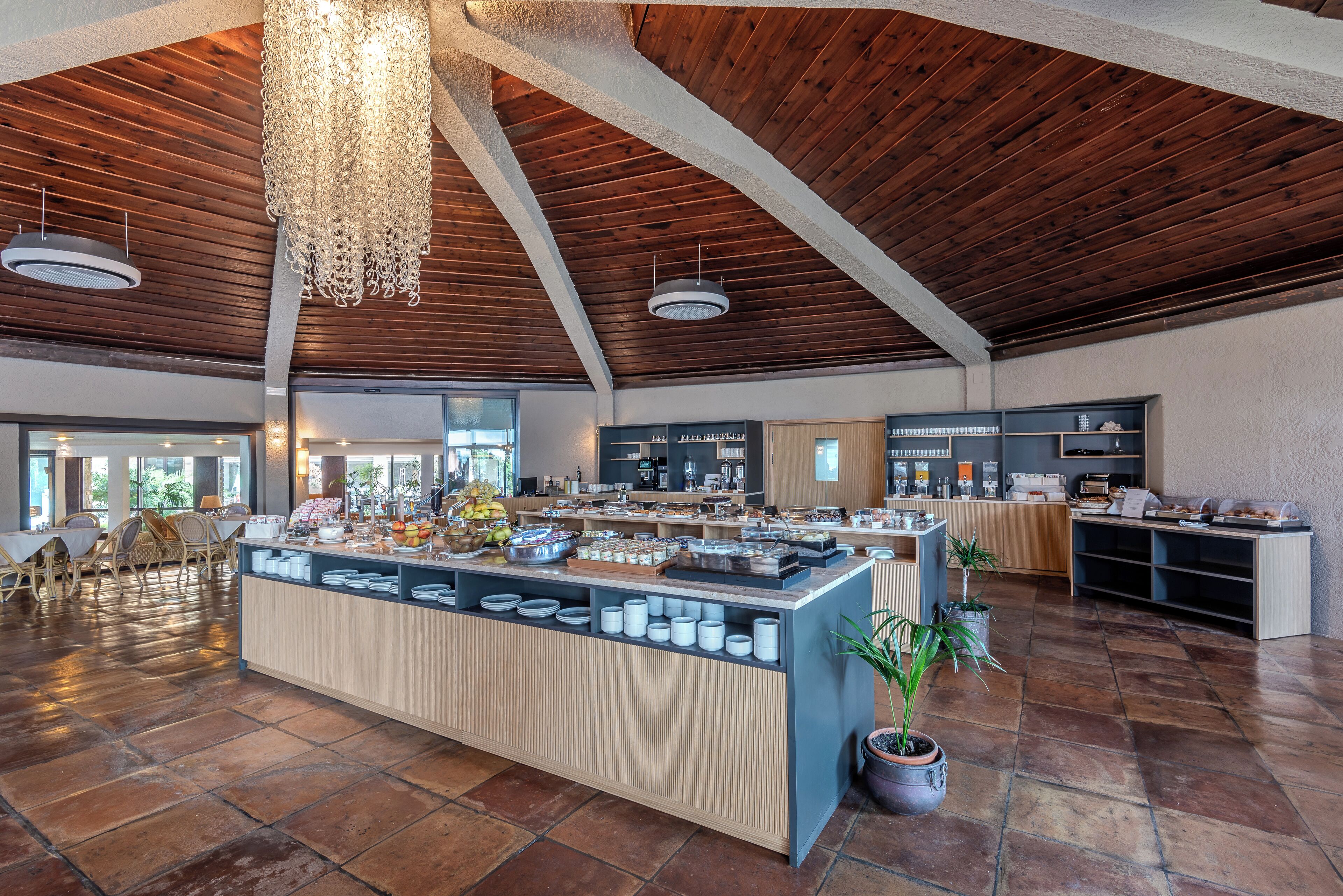 A spacious dining area with a buffet setup, wooden ceiling beams, and large windows.