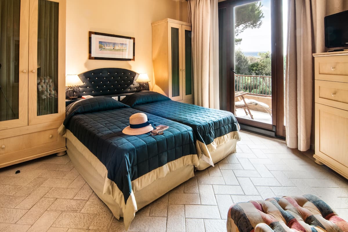 A bedroom with a large bed, a wardrobe, a television, and a balcony with a view.