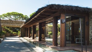 A modern building with a stone facade, wooden deck, and glass doors. - Roccamare Resort - Hotel Casa di Ponente (Castiglione della Pescaia)