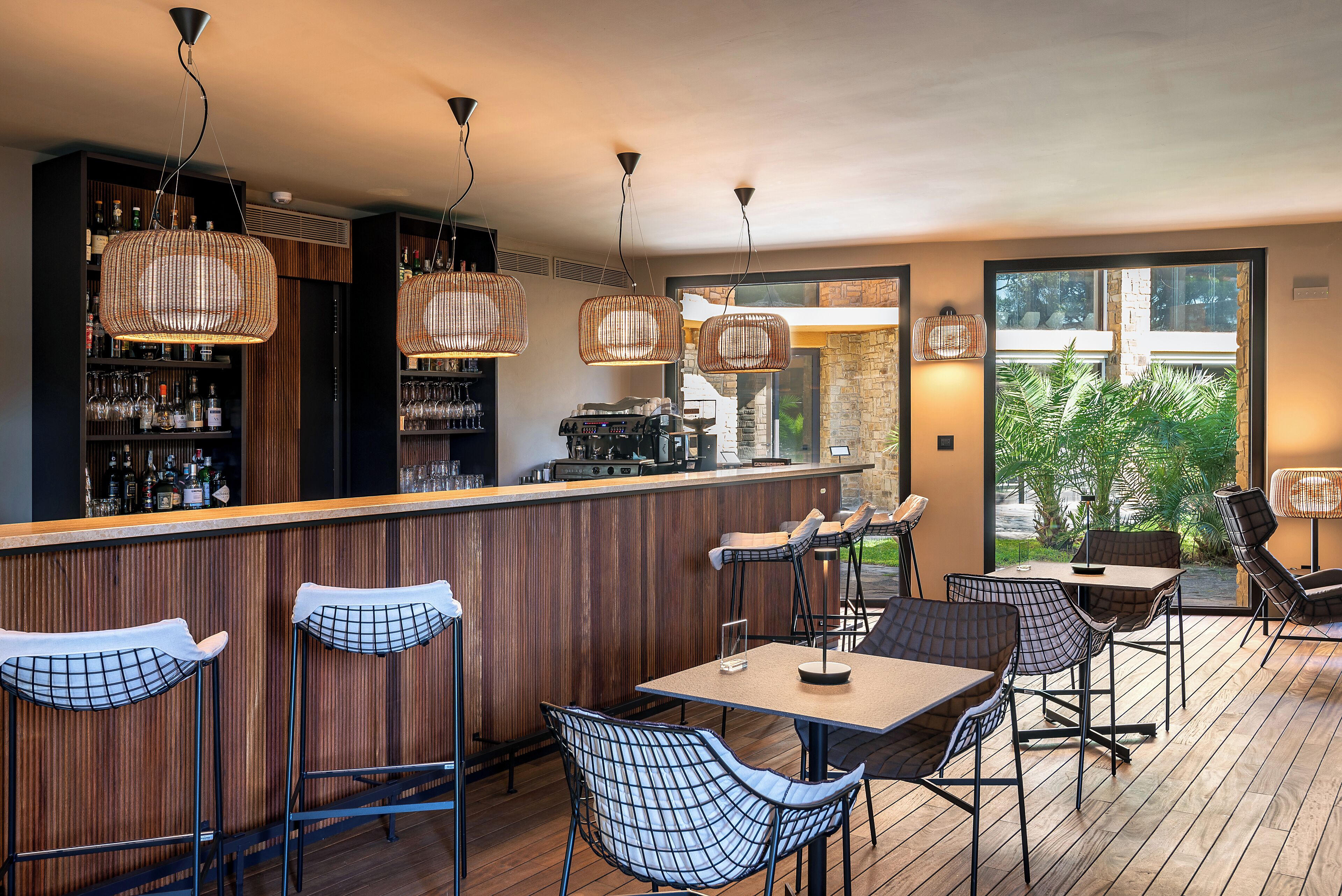 A bar area with wicker hanging lights, bar stools, and a counter with a coffee machine.