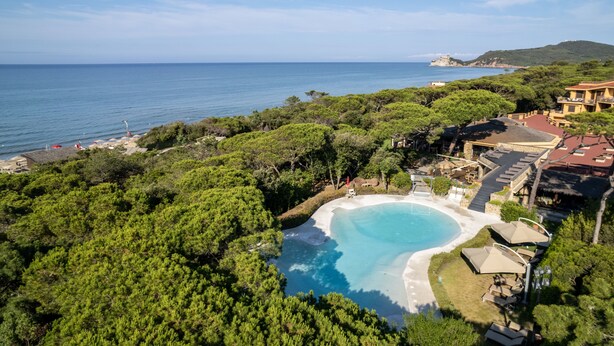 An aerial view of a resort with a large pool surrounded by lush greenery, overlooking a beach and the sea. - Roccamare Resort - Hotel Casa di Ponente (Castiglione della Pescaia)