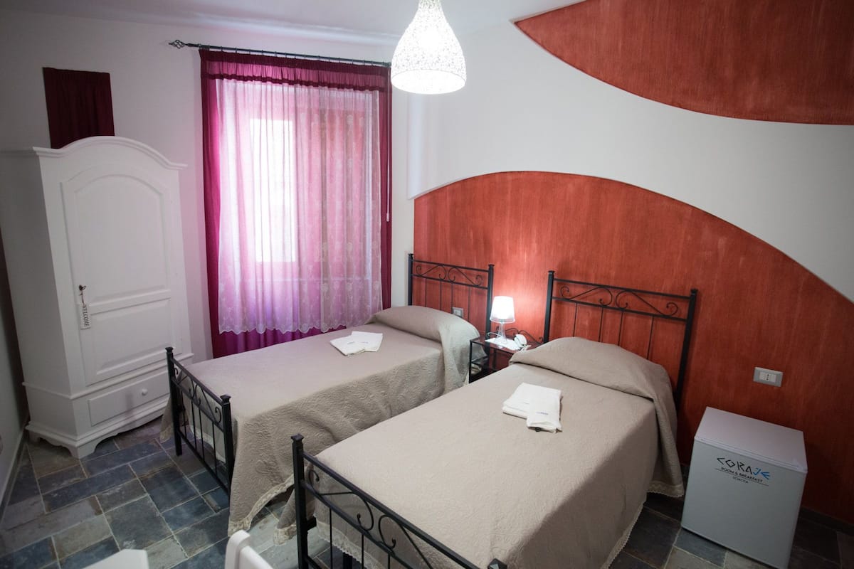Un dormitorio con dos camas, un armario, un escritorio y un radiador.