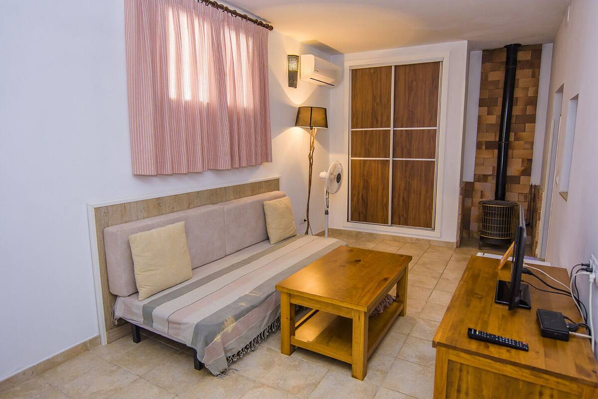 A cozy living area with a sofa, a wooden coffee table, a lamp, and a fireplace.