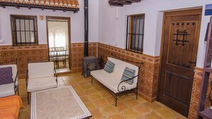 Una habitación con piso de baldosas, un sofá, una mesa y una puerta.