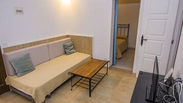 A compact room with a sofa, a small table, and a door leading to another room.