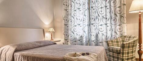 A bedroom with a bed, a chair, a lamp, and curtains.