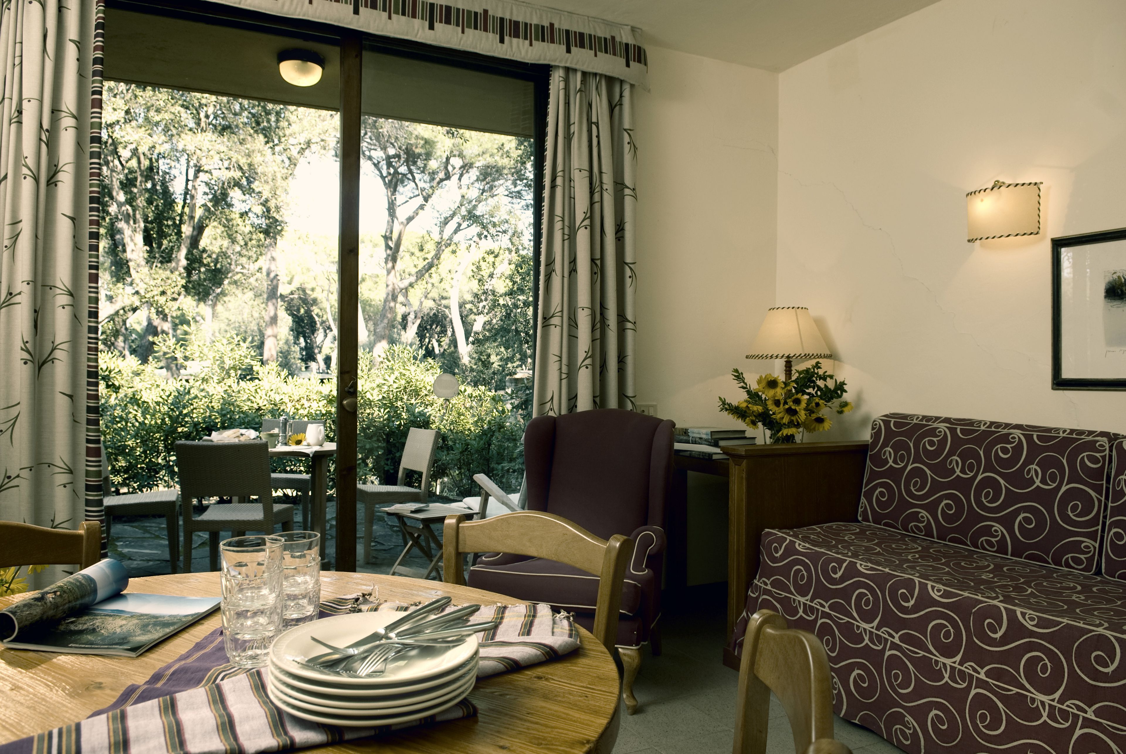 A dining area with a table set for four, a sofa, and a chair.