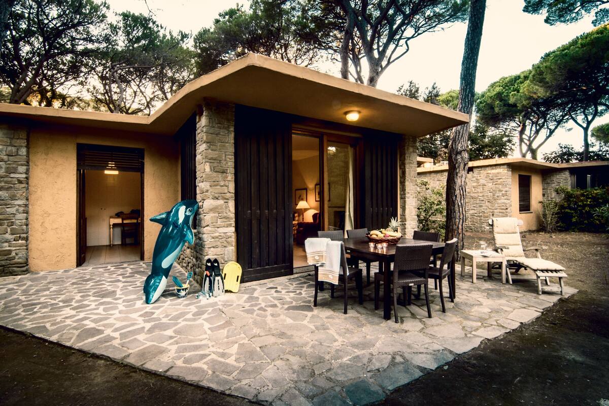 Un edificio in pietra con un patio, un tavolo da pranzo con sedie e una poltrona da relax.