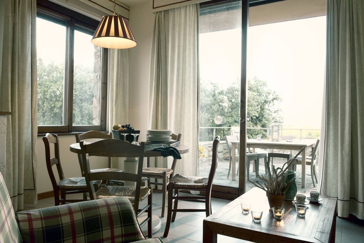 Un'accogliente sala da pranzo con un tavolo rotondo, sedie e una lampada a sospensione.