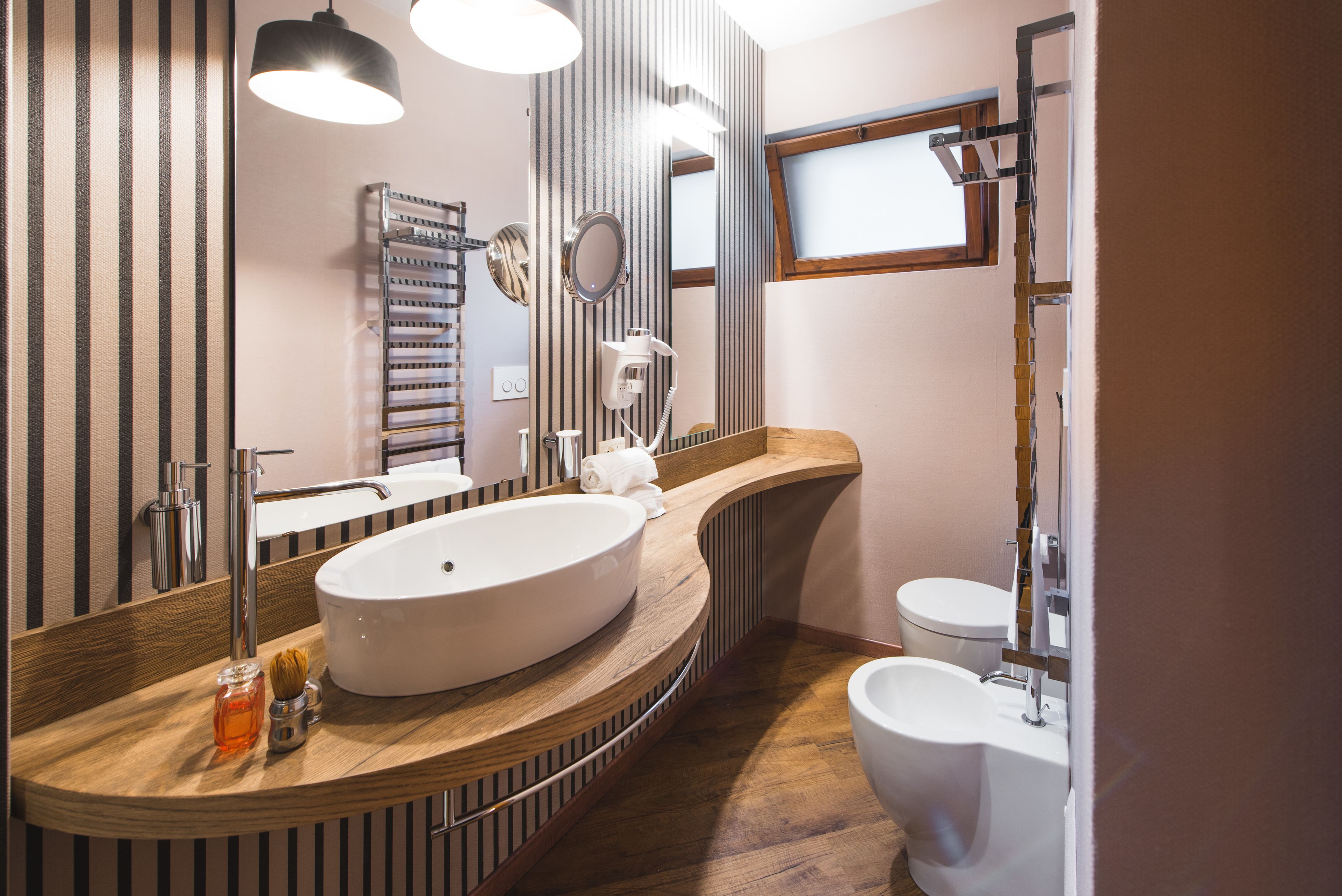 Ein modernes Badezimmer mit einem großen, ovalen Waschbecken, einer Toilette und einem Spiegel.