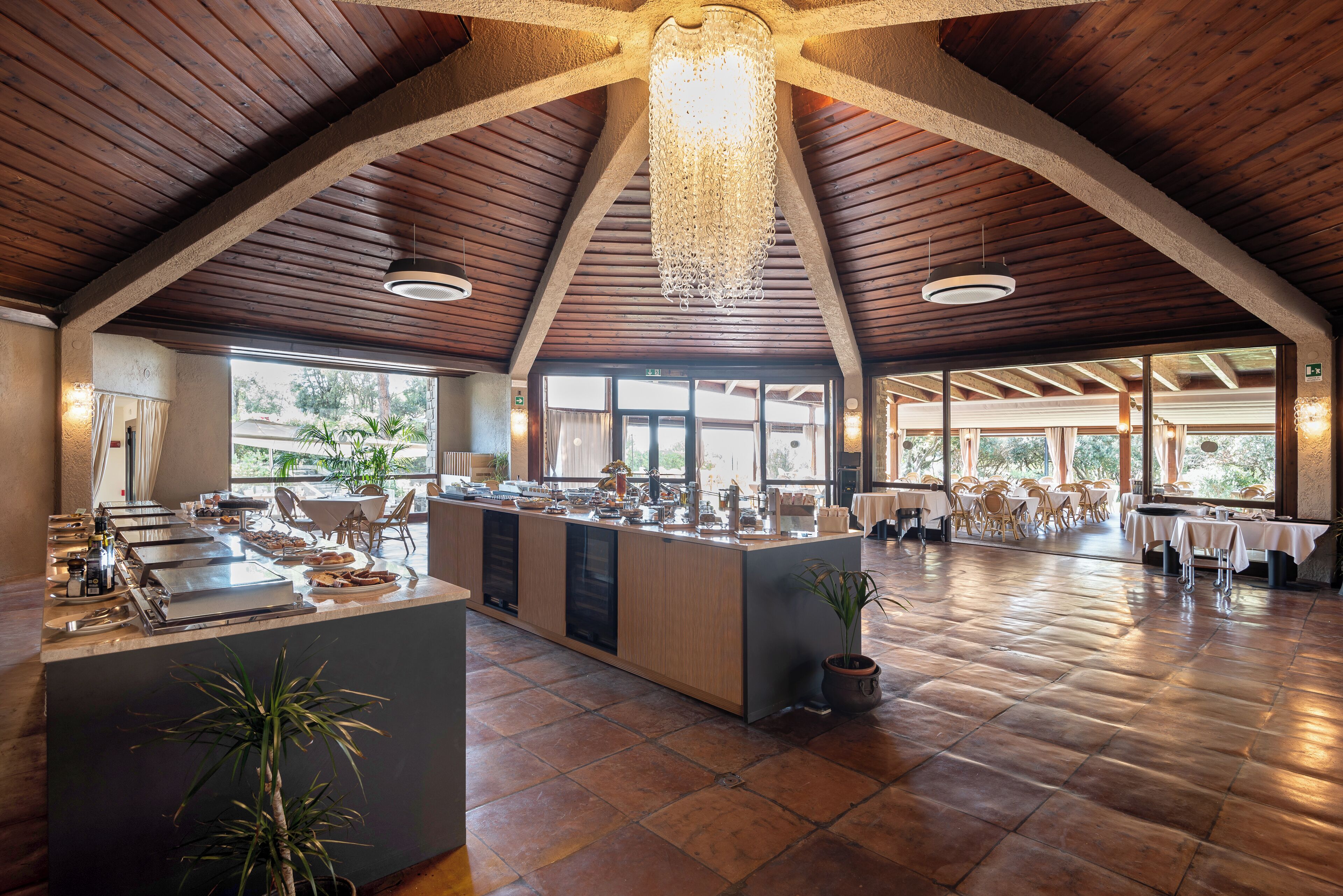 Un comedor espacioso con techo alto, vigas de madera y una isla central con electrodomésticos de cocina.