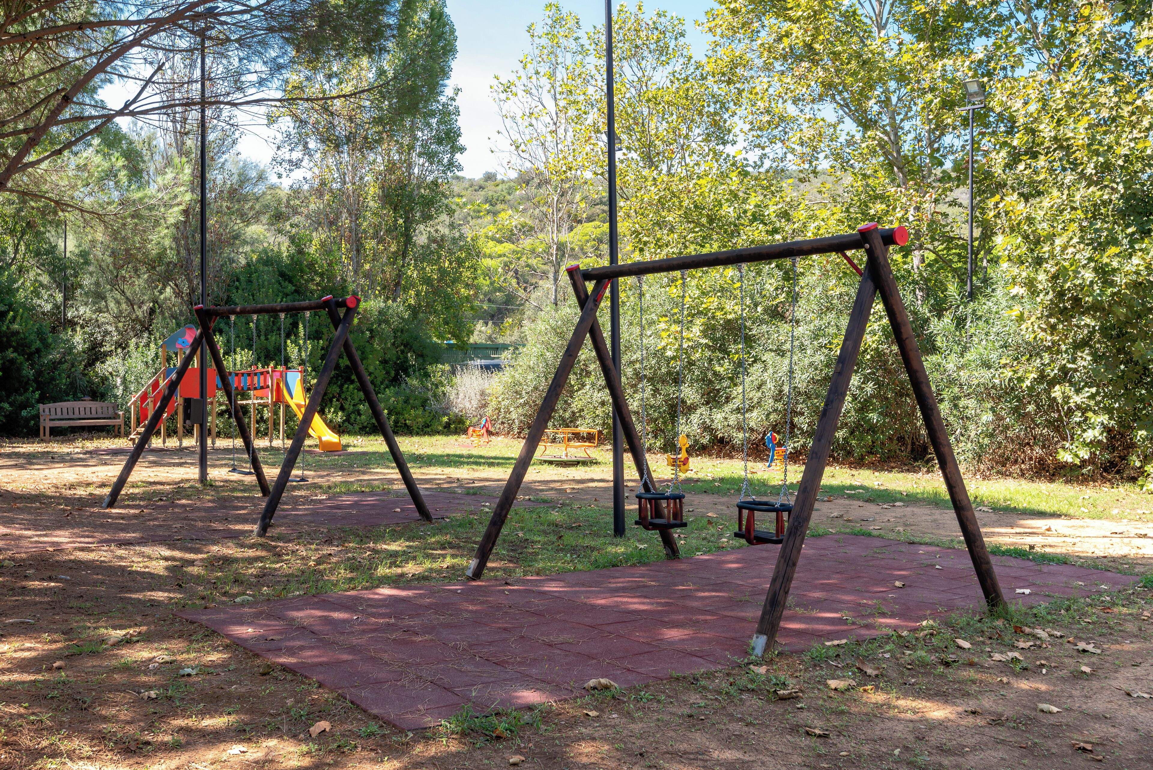 A playground with swings and a slide in a park.
