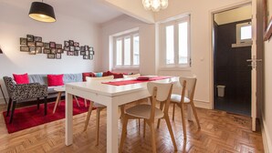 Ein Essbereich mit einem weißen Tisch und Stühlen, einem roten Teppich und einer Wand voller gerahmter Bilder.