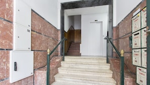 Eine Marmortreppe mit Handlauf, die zu einer Tür oben führt.