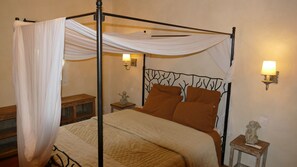 A four-poster bed with a canopy, two bedside lamps, and a nightstand with a statue. - Mas du Puits d'Amour (Orange)