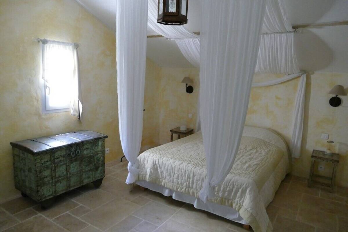 A bedroom with a bed under a canopy, a small bedside table, a nightstand, and a cabinet.