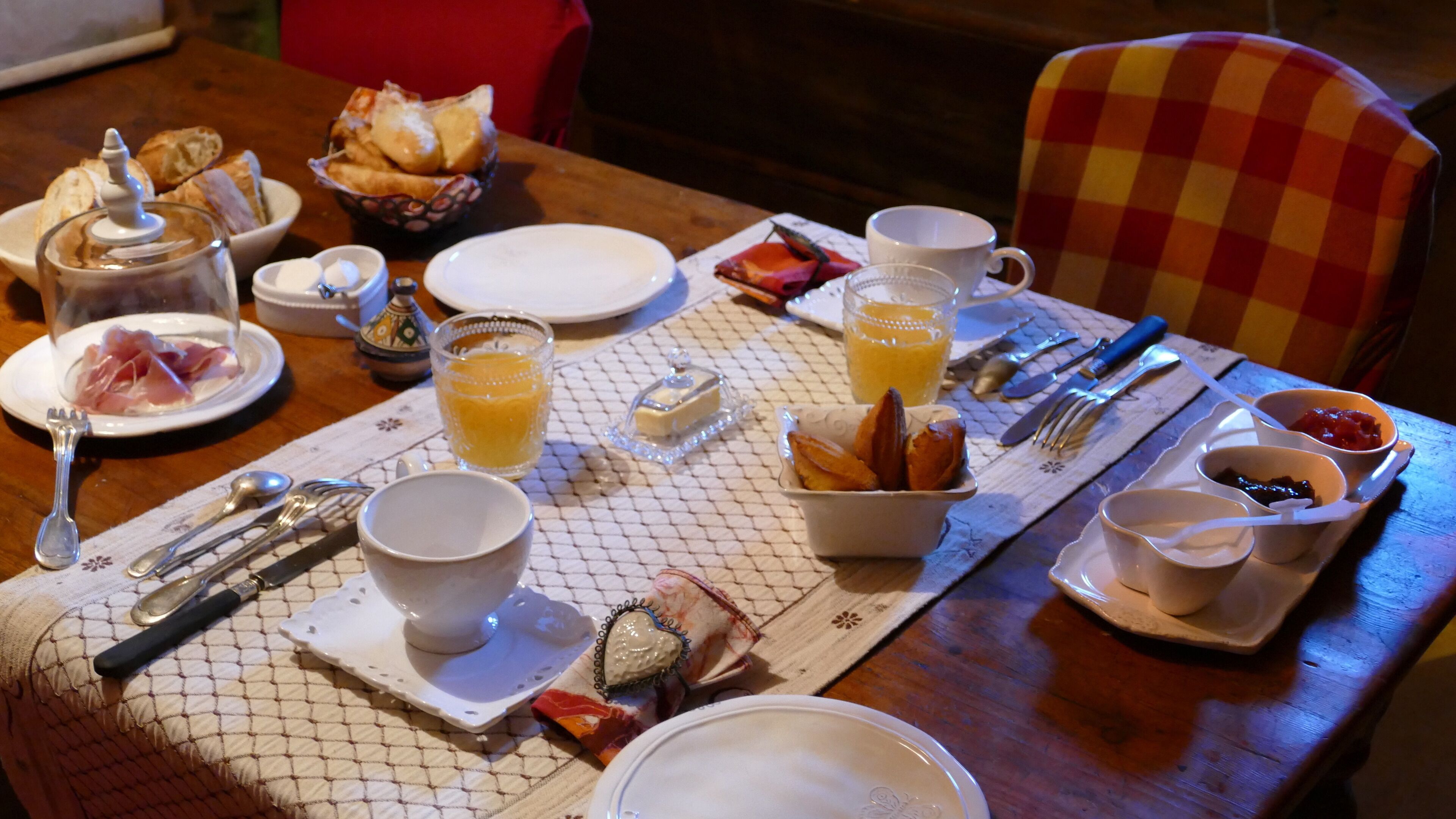 A breakfast table set with plates, bowls, cups, and cutlery.