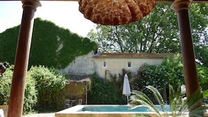 A pool area with stone walls, a pergola, and lush greenery. - Mas du Puits d'Amour (Orange)