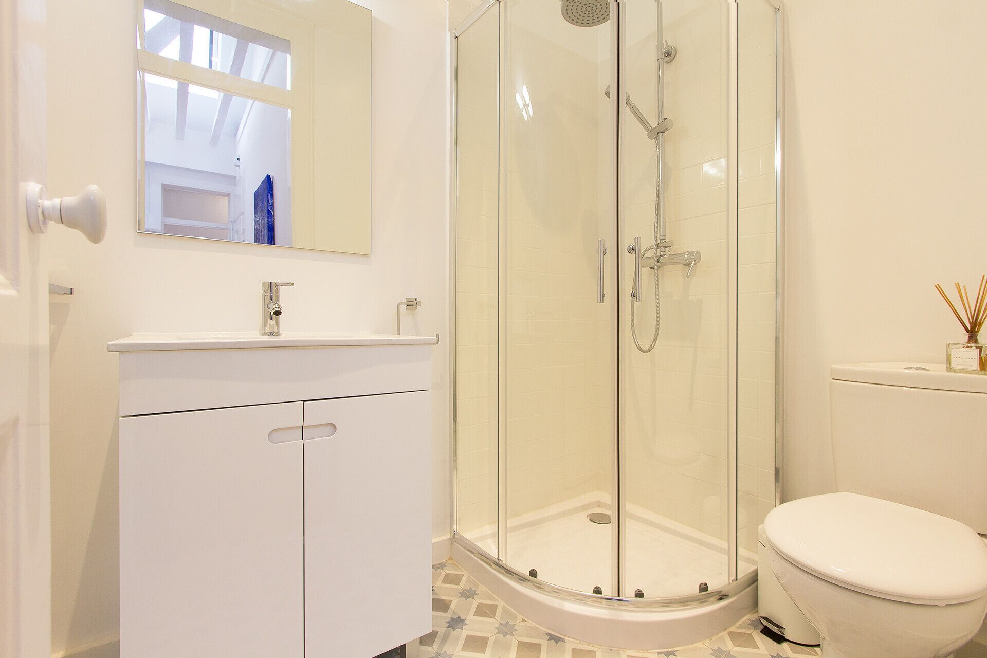 A modern bathroom with a glass-enclosed shower, a white sink, and a toilet.