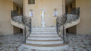 A grand staircase with intricate iron railings, a mosaic-tiled floor, and a central statue. - Apartments in Complex Poseidon (Nessebar)