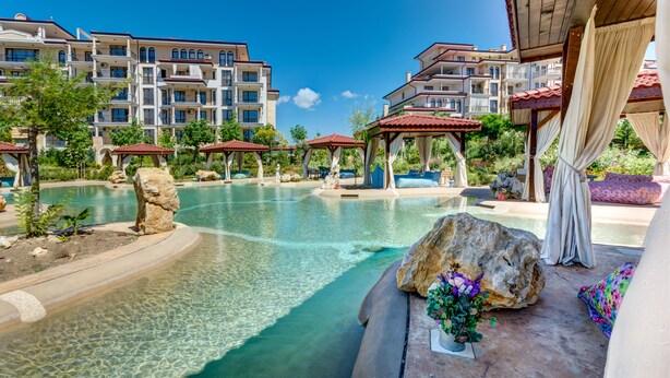 A resort pool area with clear water, lounge chairs, and a gazebo. - Apartments in Complex Poseidon (Nessebar)