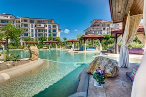 A resort pool area with clear water, lounge chairs, and a gazebo. - Apartments in Complex Poseidon (Nessebar)
