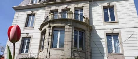 A large, two-story building with a curved corner balcony and multiple windows.