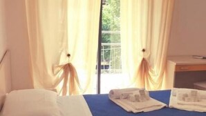 Una habitación de hotel con cama, escritorio y ventana con cortinas.